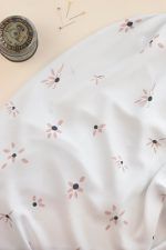 Tela de ecoviscosa color blanco roto con flores margaritas de color rosa y a las que se le están cayendo algunos pétalos