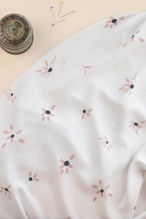 Tela de ecoviscosa color blanco roto con flores margaritas de color rosa y a las que se le están cayendo algunos pétalos
