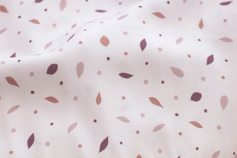 Detalle de la tela rosa claro con pequeñas hojas de color rosa oscuro, marrón y granate.