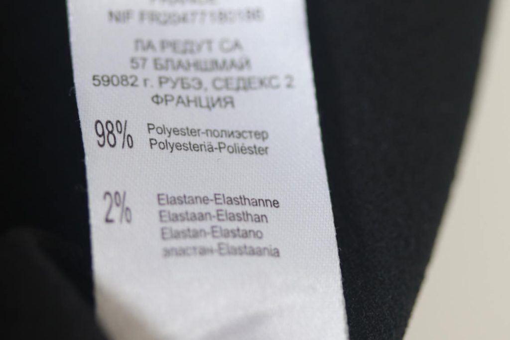 Etiqueta de tela de una prenda en la que se lee que está compuesta de un 98% poliéster y de un 2% de elastano.