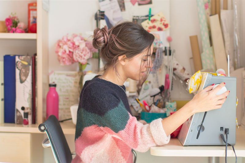 Laura, una mujer joven, en su estudio de costura, cose con una máquina de coser