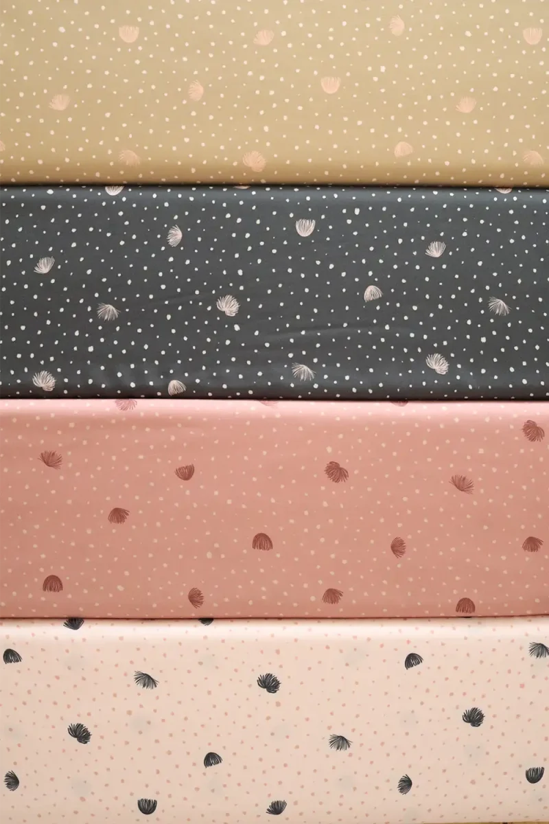 Cuatro tablas de tela con patrones de puntos y delicados dientecitos de león de colores pasteles que oscilan entre el blanco crema y el dorado sutil y detalles en rosa y el negro.