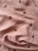 Plano cercano de una viscosa, con partes dobladas para ver el comportamiento de la tela. Es de color rosa arcilloso, con puntitos irregulares en color beige y con flores del árbol de la seda en color arcilla oscuro.