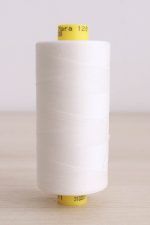 Bobina de hilo Gütermann Mara 120, de color blanco crudo, sobre una madera de color claro y de fondo una pared blanca.
