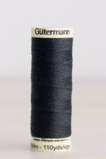 Bobina de hilo Gütermann 542, de color gris muy oscuro, sobre una madera de color claro y de fondo una pared blanca.