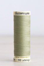 Bobina de hilo Gütermann 282, de color verde, sobre una madera de color claro y de fondo una pared blanca.