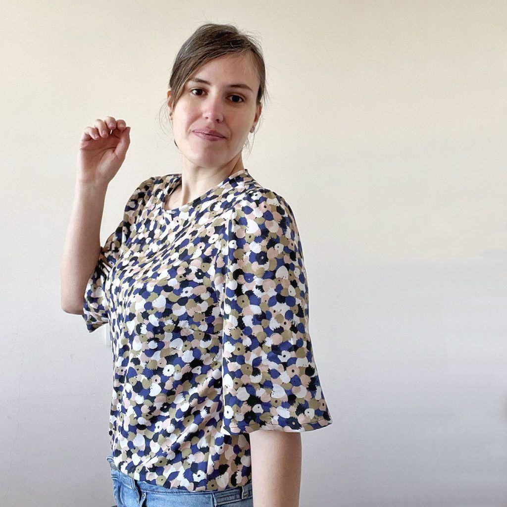 Mujer de pelo castaño luce una hermosa blusa Mille Friori con estampados en tonos pastel y azul.