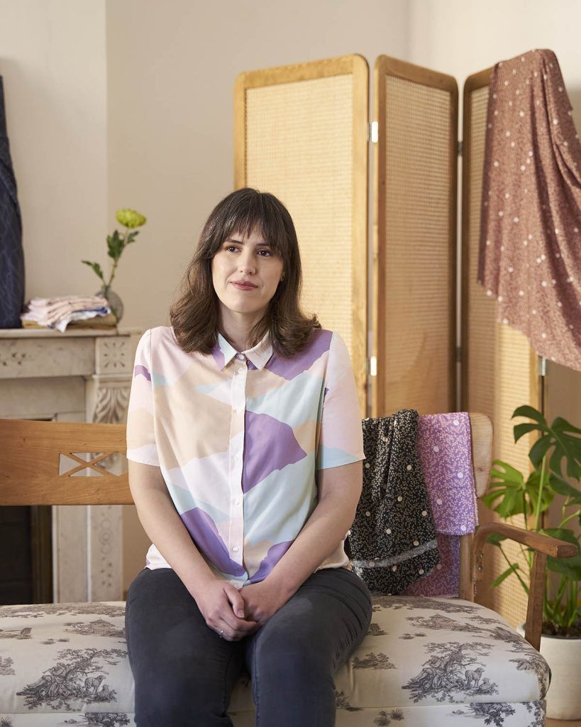 Mujer de pelo castaño luce una camisa de tela viscosa sostenible con patrones triangulares en tonalidades pasteles que evocan las montañas, exclusiva de la marca ODALOA.