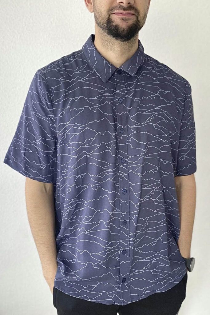 Plano americano de un hombre con barba recortada que posa, con manos en los bolsillos, frente a la cámara. Lleva una camisa confeccionada con la viscosa ecovero Horizonte azul.