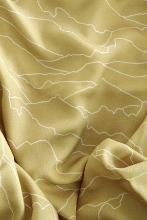 Tela color golden (oro, pastel) con patrones que evocan el horizonte en líneas blancas.