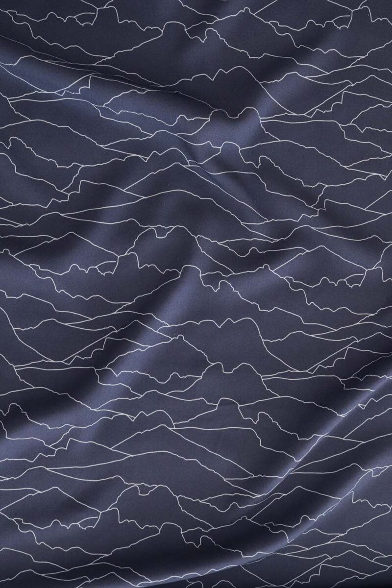 Tela azul oscuro en la que aparecen líneas en color blanco entrelazadas entre sí. Estas líneas son el contorno de diferentes montañas de la geografía española, como el Monte Oroel, Naranjo de Bulmes, Pedraforca, peñas de Islallana, peñas de Aya, el Teide, pico del lobo, sierra de la Tramuntana con el pico Puig Major, Veleta, entre otros.