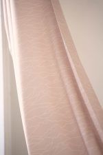 Tela horizonte con patrones de líneas blancas sobre tela sostenible de color rosa pastel.