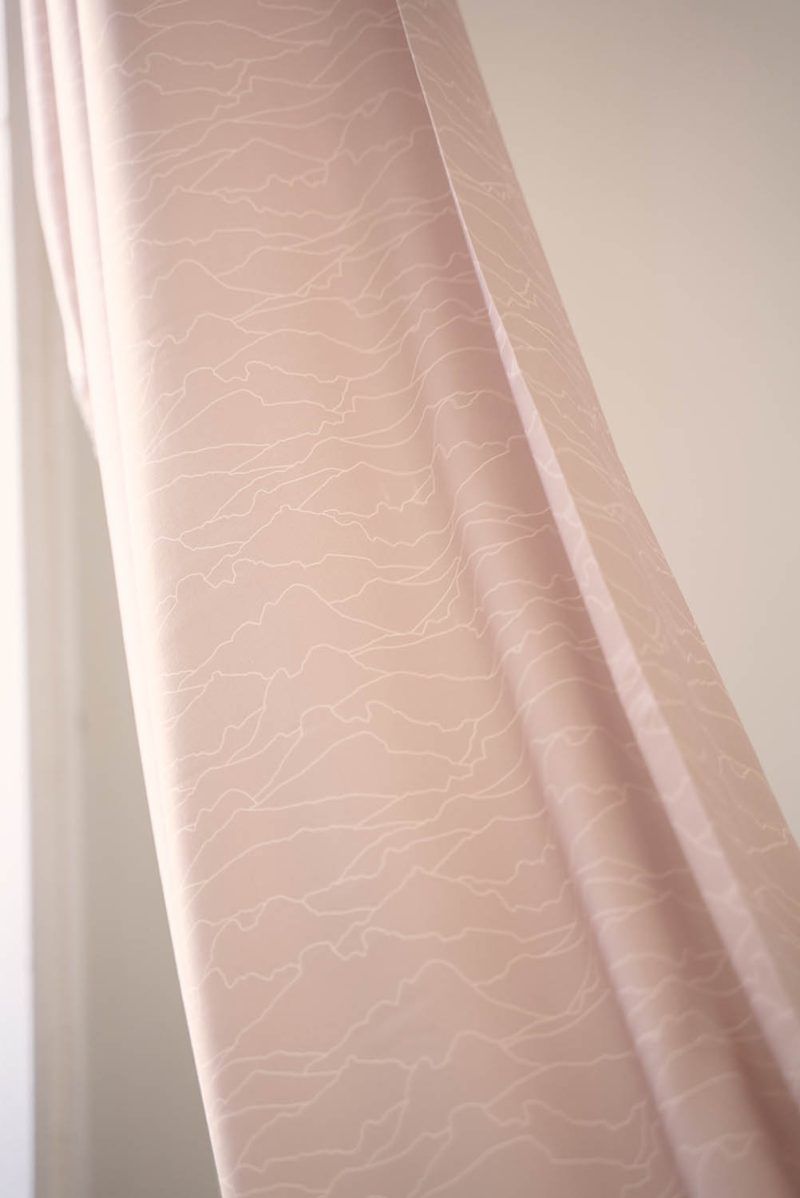 Tela horizonte con patrones de líneas blancas sobre tela sostenible de color rosa pastel.