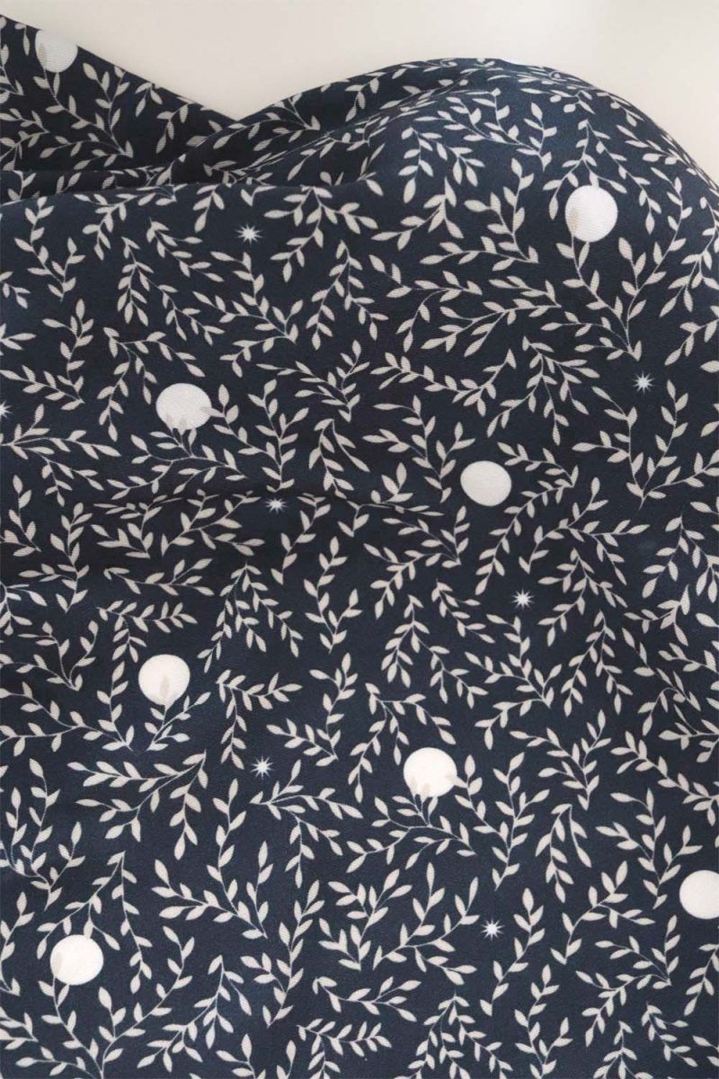 Luna marino Tela, de aspecto fluido, de color azul marino con hojas color blanco y topos blancos.