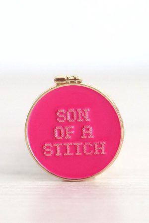 Porta agujas imantado. Tiene forma de bastidor de bordar redondo. Es de color fucsia y en el se puede leer "son of a stitch".