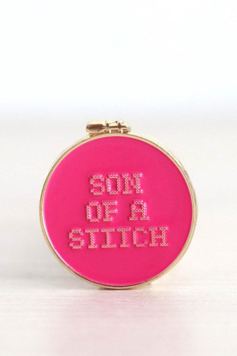 Needle_minder_son_of_a_stitch Porta agujas imantado. Tiene forma de bastidor de bordar redondo. Es de color fucsia y en el se puede leer "son of a stitch".
