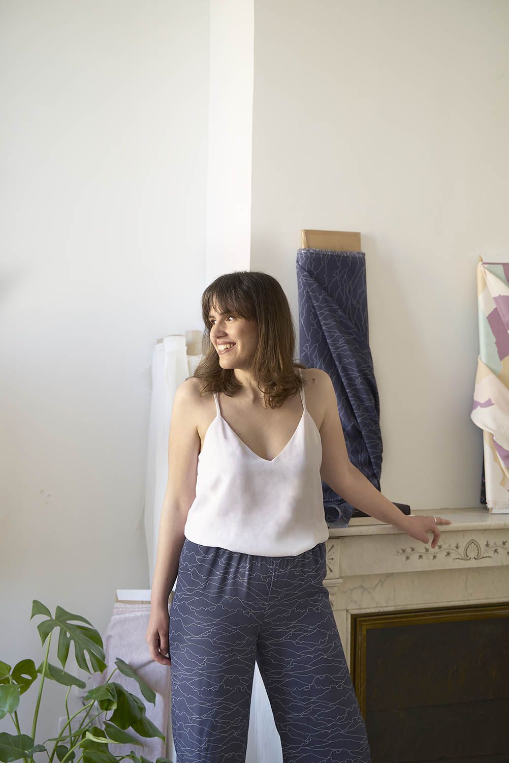 Mujer modela hermoso diseño textil de pantalones con estampado "Horizonte". En tela color azul.