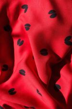 Ecoviscosa de huellas en color rojo Tela de viscosa haciendo ondas, de color rojo intenso con motivos de huellas de ciervo en color azul oscuro casi negro.