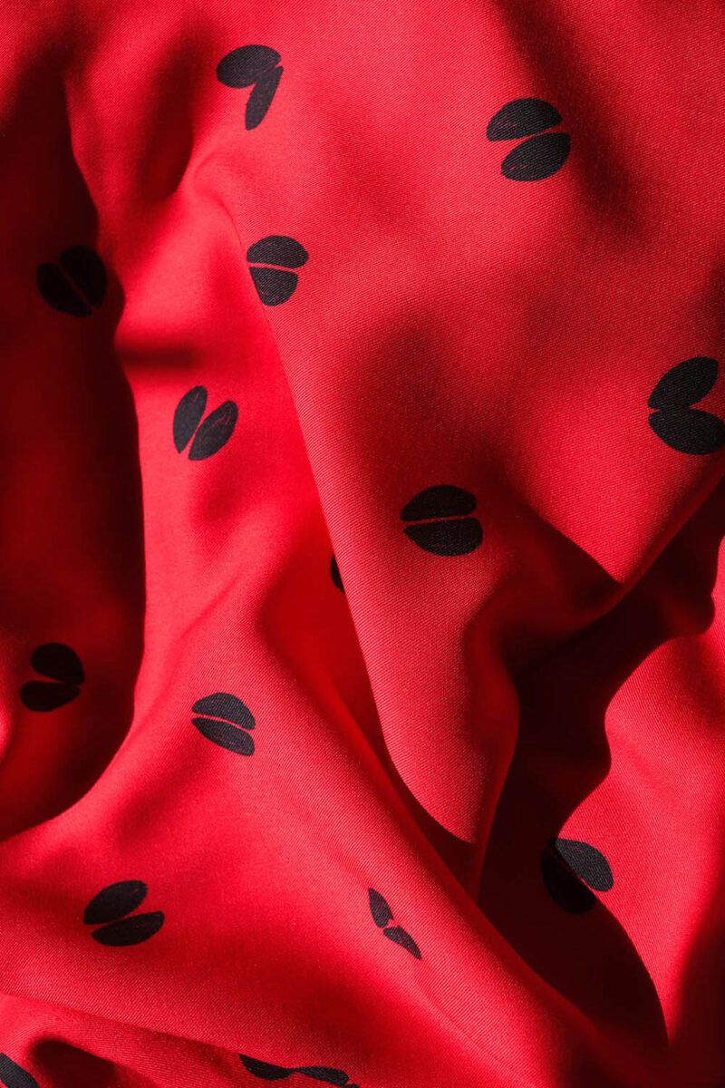 Ecoviscosa de huellas en color rojo Tela de viscosa haciendo ondas, de color rojo intenso con motivos de huellas de ciervo en color azul oscuro casi negro.