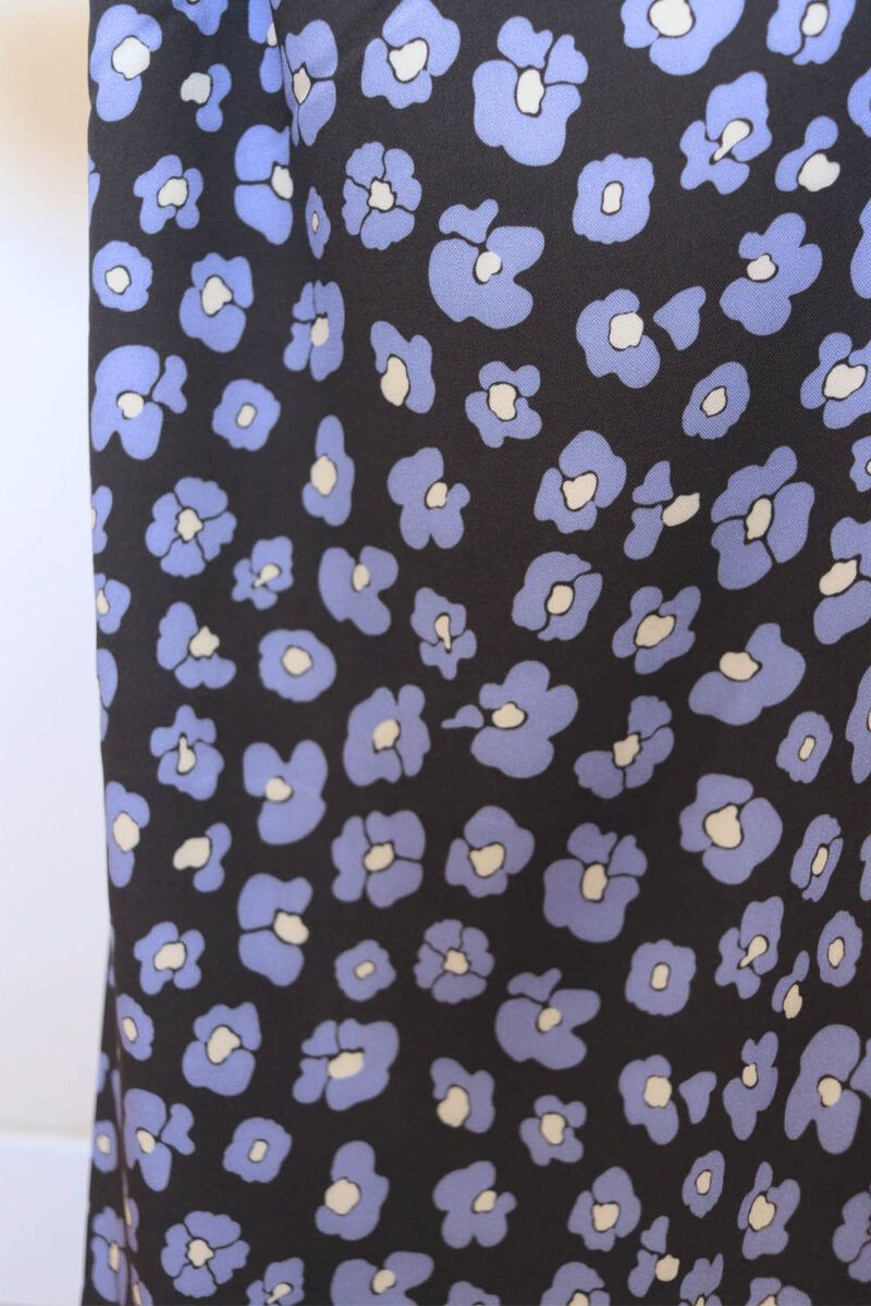 Salvaje azul Tela de fondo negro con flores que imitan las manchas de leopardo en color azul y centro color mantequilla