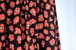 Una tela de fondo negro con flores que imitan las manchas de leopardo en color rojo coral y centro blanco.