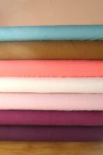 Tablillas de telas de punto camiseta de algodón orgánico en diferentes colores (aguamarina, aceituna, coral, natural, rosa palo, plum y mora) apiladas una encima de la otra