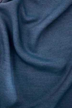 Primer plano de una tela de Tencel en azul denim. La tela no está completamente estirada, si no que hace surcos mostrando el comportamiento de una tela con caída.