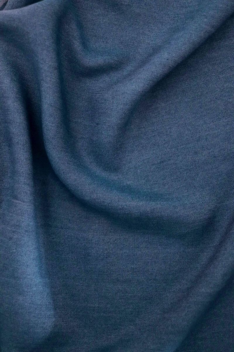 Tela Tencel Denim azul Primer plano de una tela de Tencel en azul denim. La tela no está completamente estirada, si no que hace surcos mostrando el comportamiento de una tela con caída.