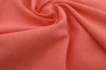 Plano cerca de la textura de una tela de punto camiseta de algodón orgánico en color coral