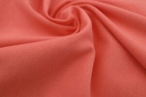 Plano cerca de la textura de una tela de punto camiseta de algodón orgánico en color coral