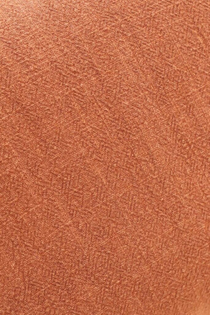 Detalle cercano de una tela de ramio, de aspecto rústico y de color ladrillo.