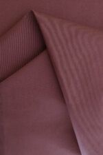 Tela de gabardina Tela de gabardina rosa terracota que hace unos pliegues sobre sí misma.
