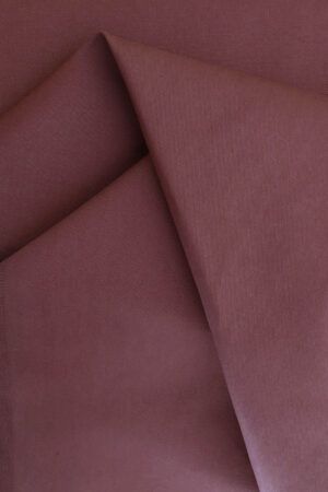 Tela de gabardina rosa terracota que hace unos pliegues sobre sí misma.
