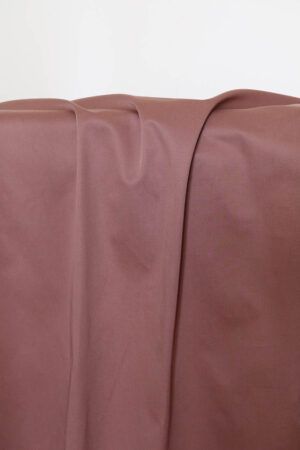 Tela de gabardina de color rosa terracota que cuelga y hace unos pliegues