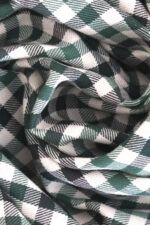 Plano detalle de una tela de sarga de algodón de cuadros en distintos tono de verde y crudo. Se puede apreciar las líneas diagonales características de una sarga.