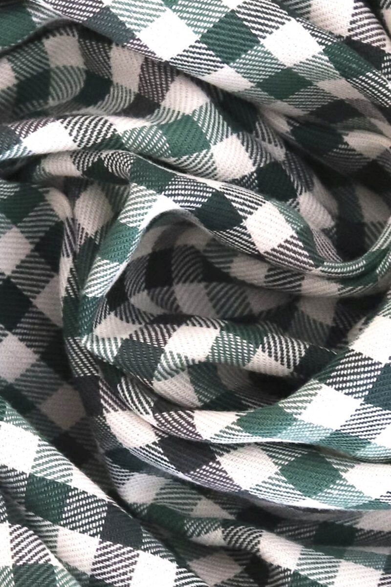 Plano detalle de una tela de sarga de algodón de cuadros en distintos tono de verde y crudo. Se puede apreciar las líneas diagonales características de una sarga.