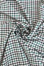 Tela de sarga de algodón de cuadros en distintos tono de verde y crudo. La tela hace dobleces en forma de círculo.