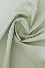 Tela pantalones stretch verde Tela de sarga stretch de color verde claro con dobleces haciendo forma de espiral.