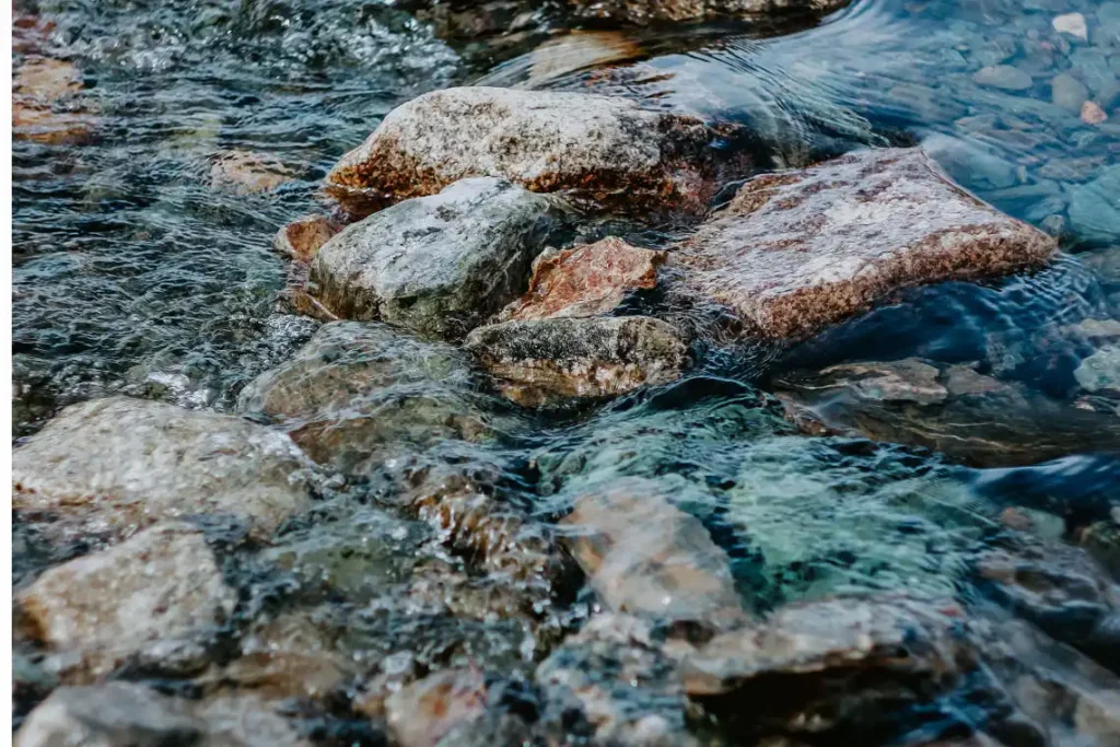 Piedras grandes sobresalen en un río de poca profundidad con aguas cristalinas.